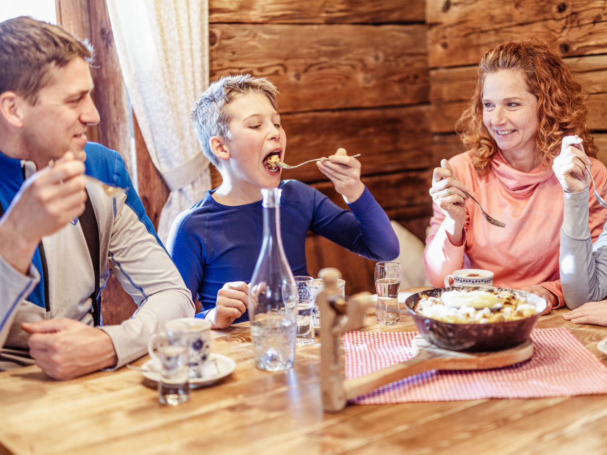 Familie beim Kaiserschmarrn essen auf einer Hütte
