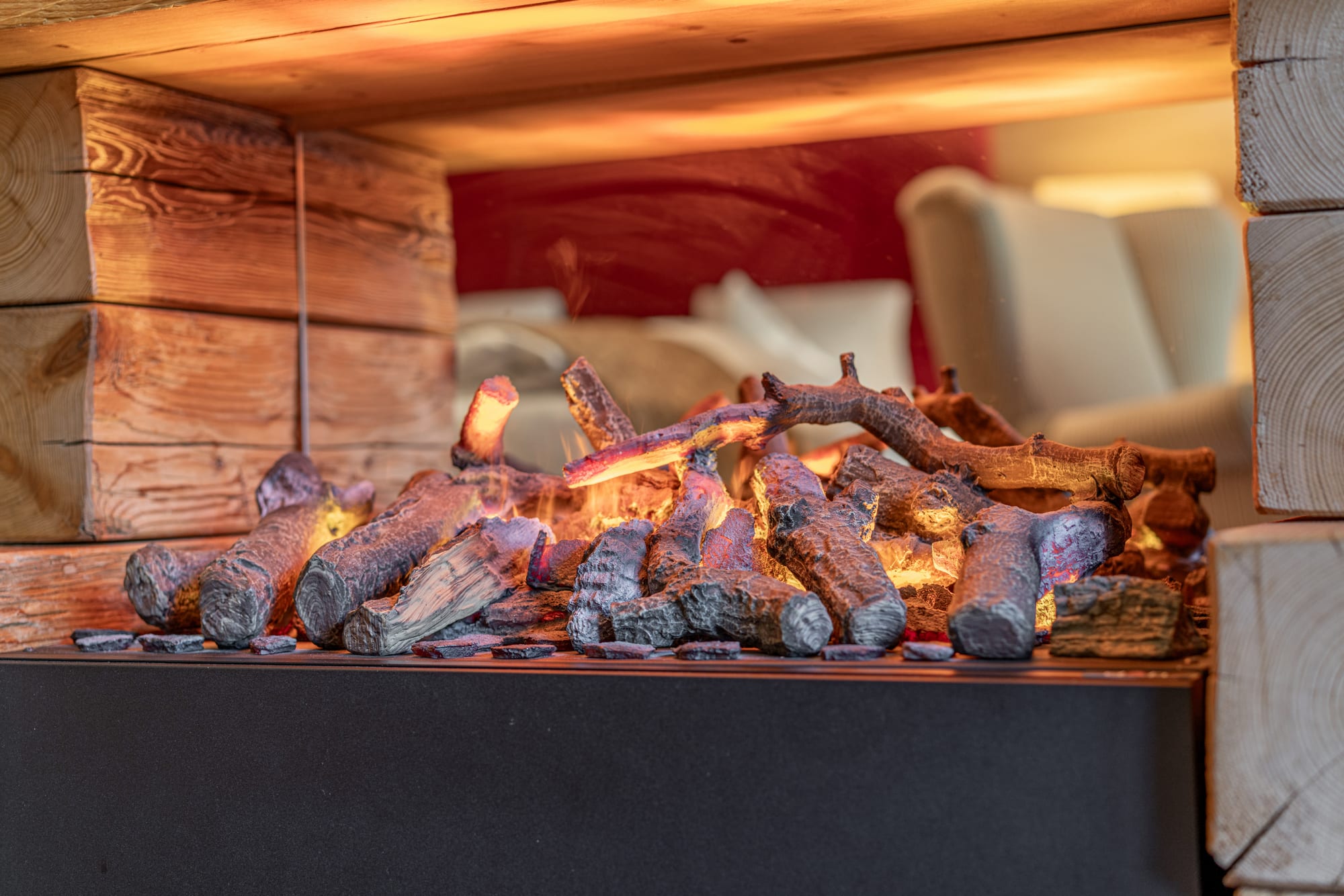 eingeschalteter LED-Kaminofen mit Spiegel, in dem sich das Bett und ein Stuhl spiegelt