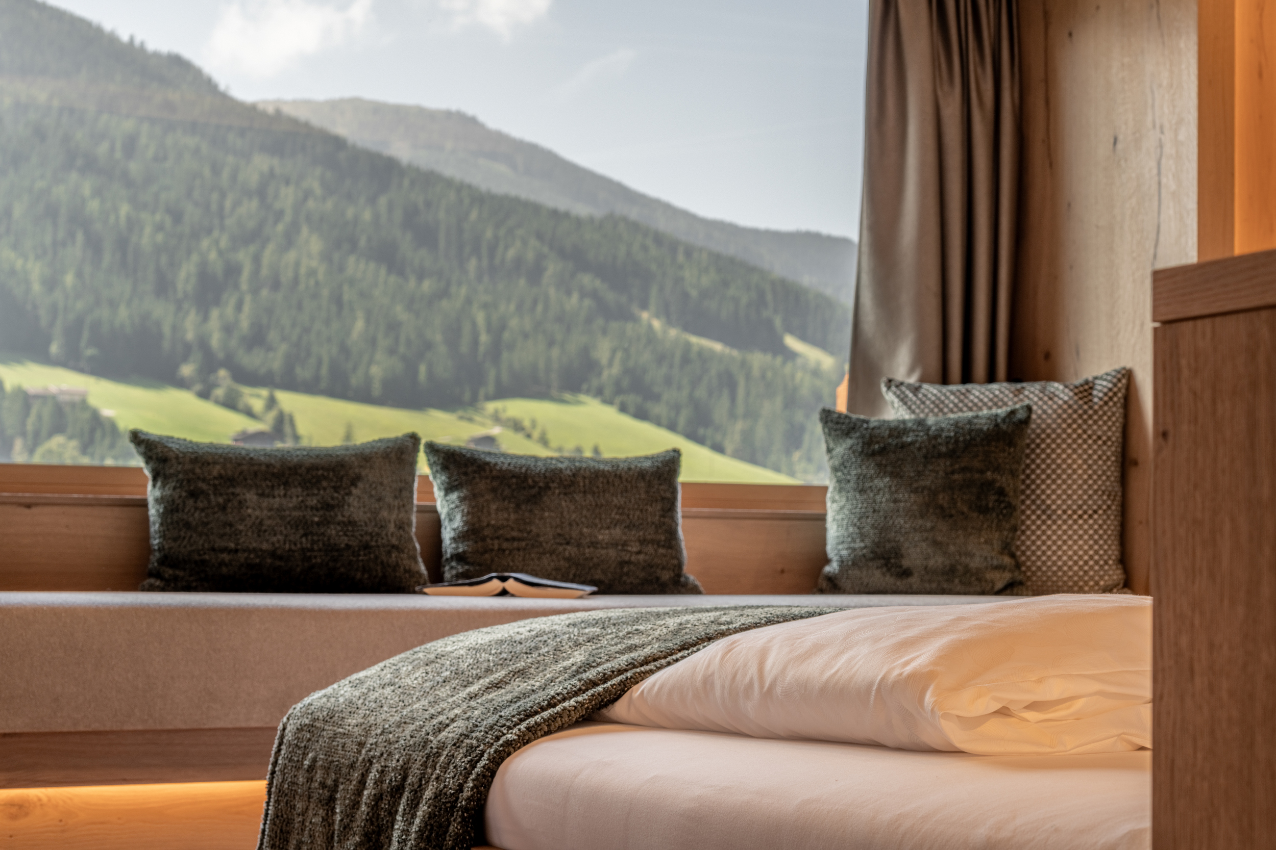 Alpbacherhof_Relax-Suite Traumblick_Bett_Liege beim Fenster und Panoramablick