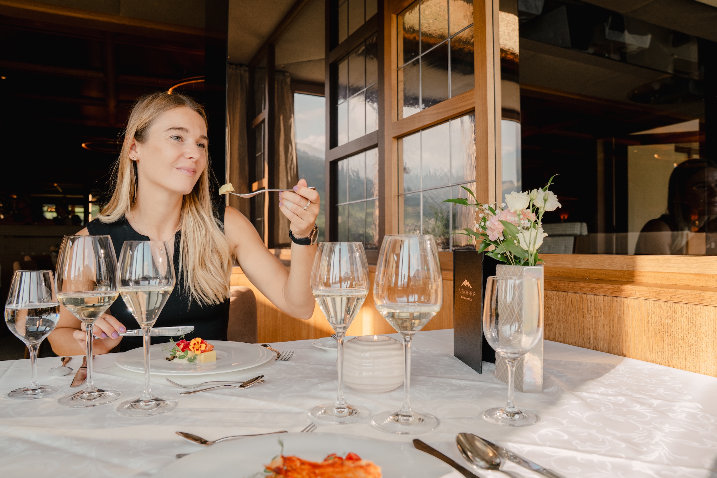 Frau genießt das 6-Gang-Abendmenü mit Weinbegleitung im Panoramarestaurant des Hotel Alpbacherhof in Tirol
