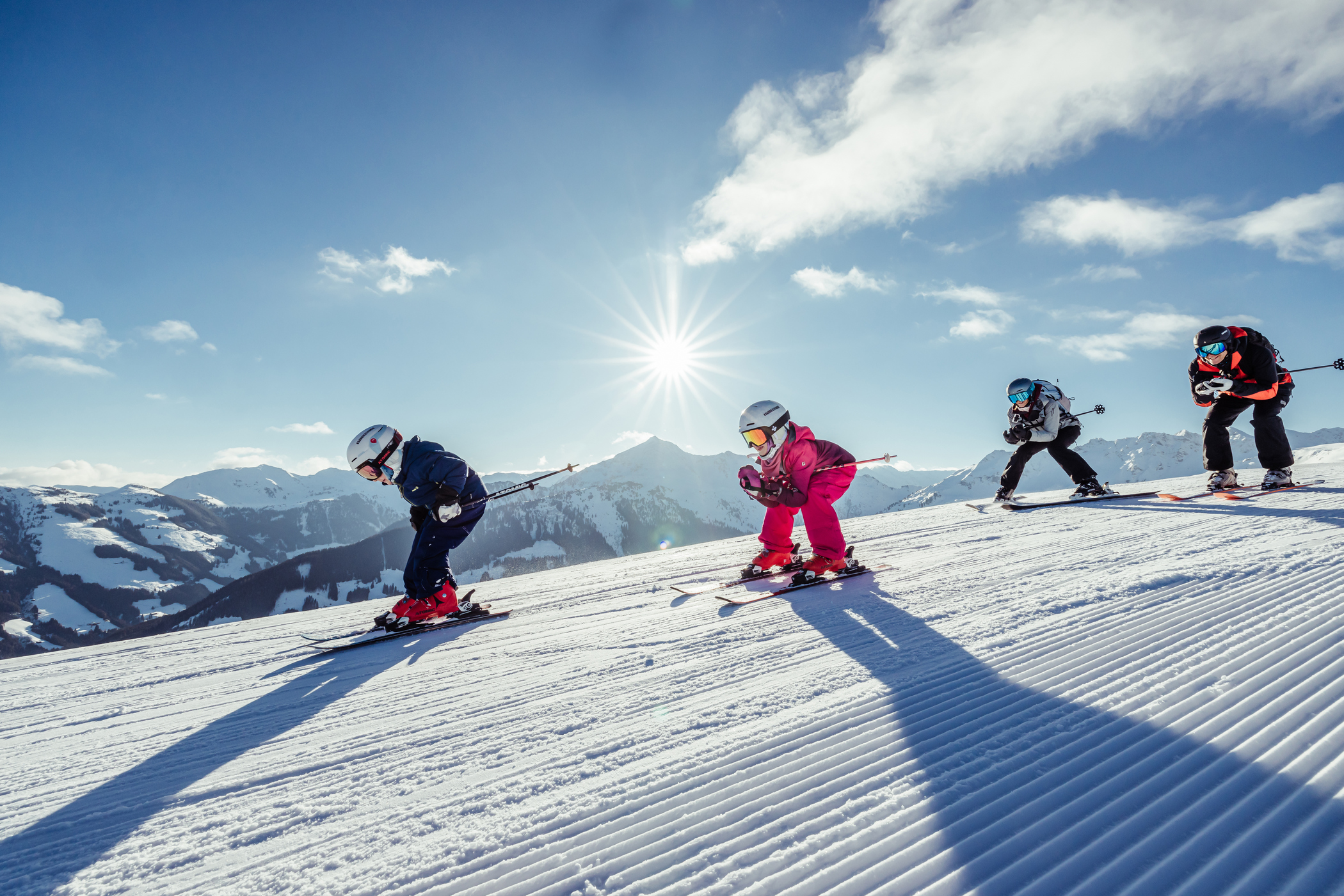 Familie mit Kindern Schussfahrt mit Ski am Berg sonnig