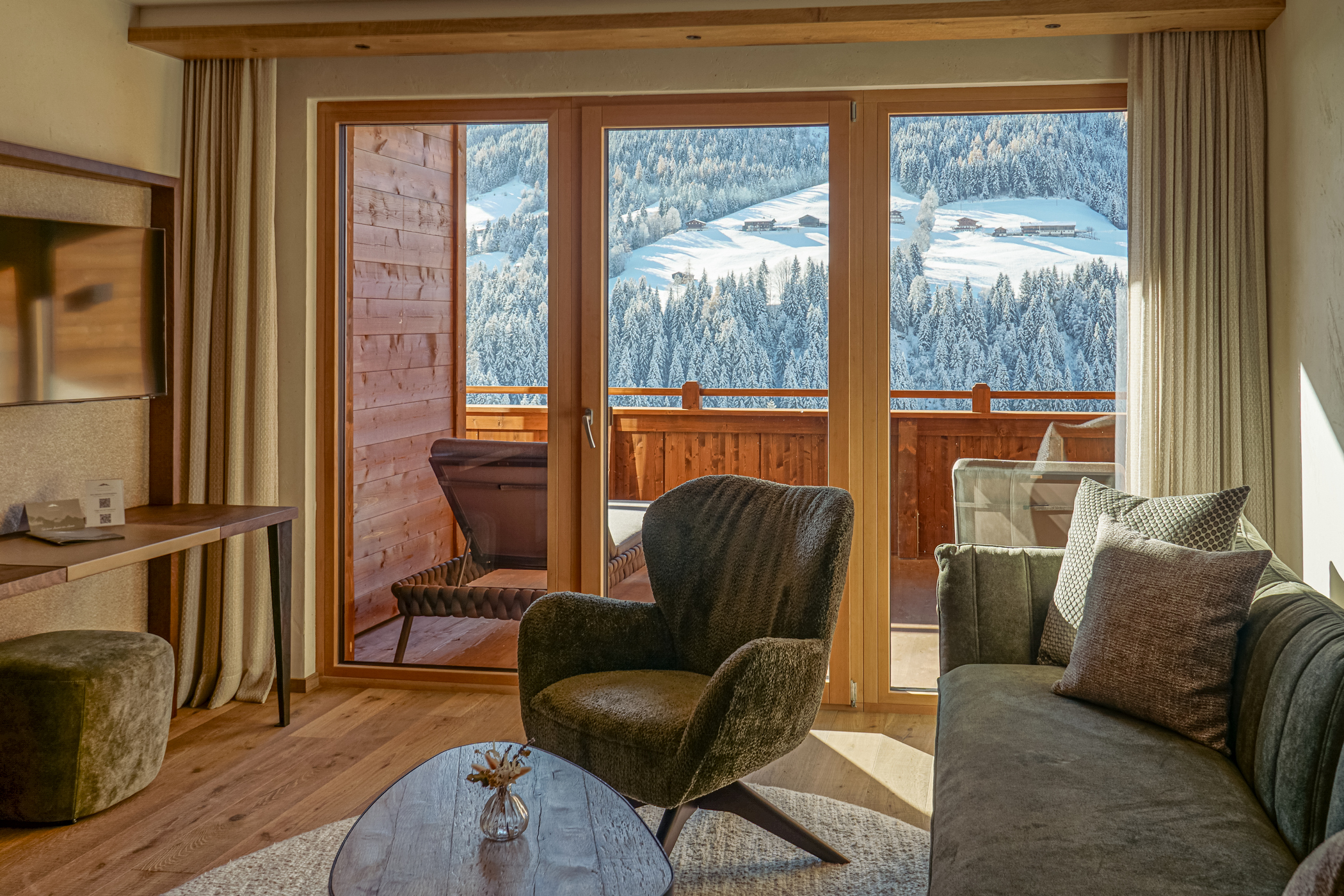 Sessel, Sofa und Fernseher in der Relax Suite des Alpbacherhof mit Balkon und Liegestuhl und Panoramablick übers Alpbachtal