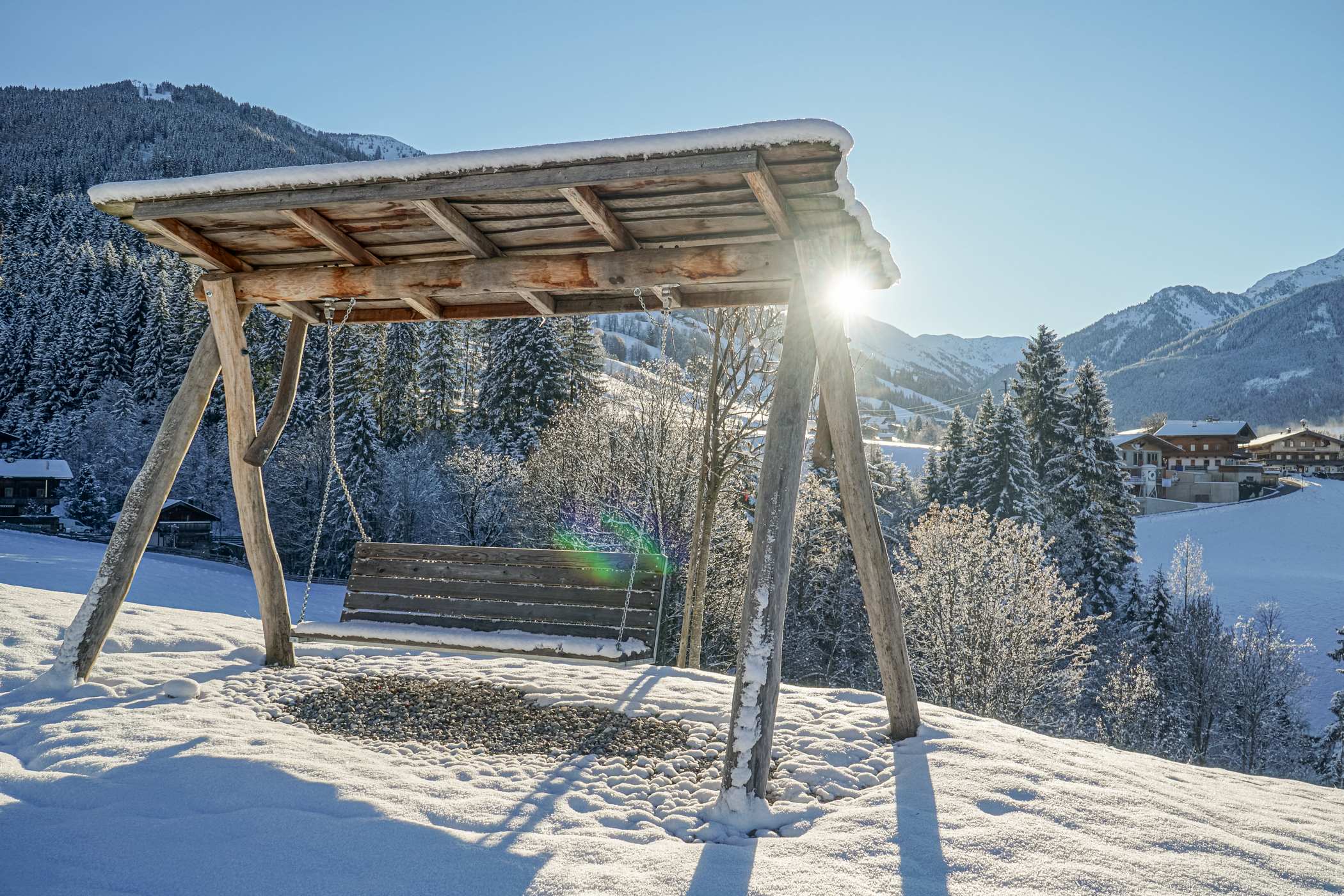 Schaukel im Garten vor dem Hintergrund einer winterlichen tief verschneiten Berglandschaft