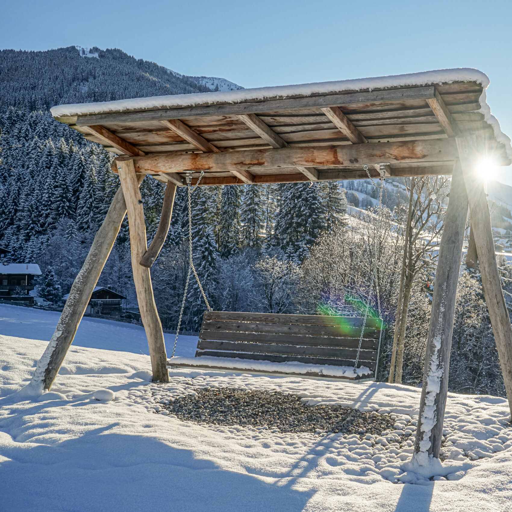 Verschneiter Garten mit Schaukel vor Bergkulisse