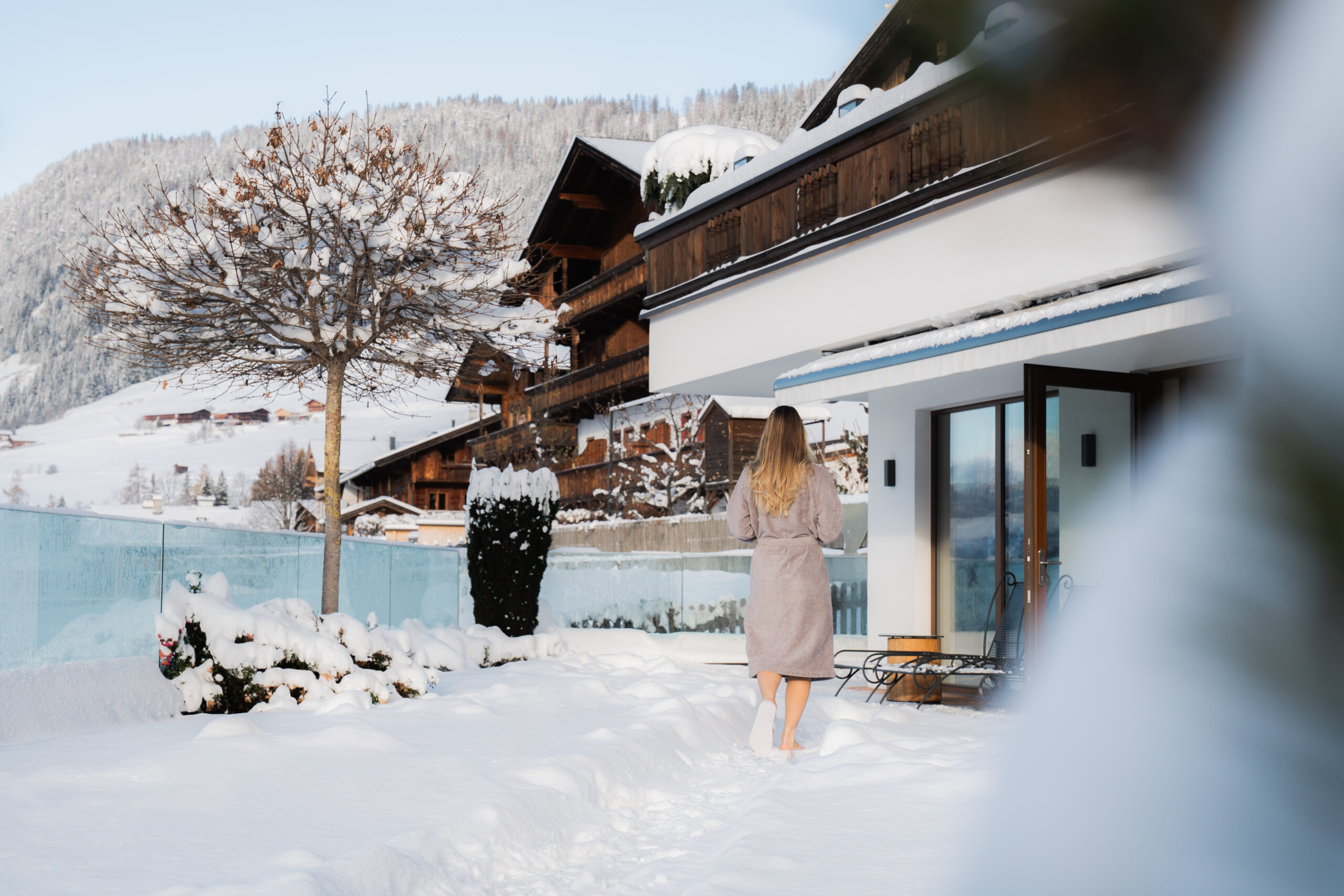 Frau im winterlich verschneiten Garten des Wellnesshotels Alpbacherhof im Alpbachtal Tirol