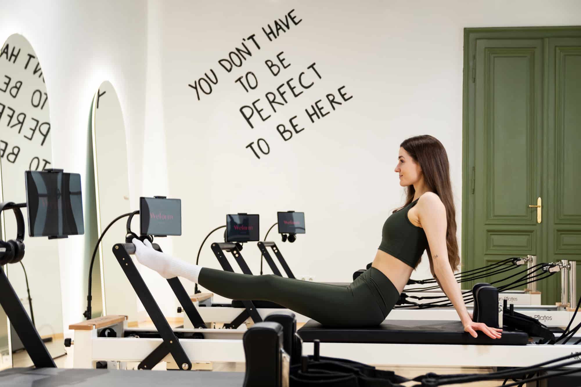 Reformer Pilates Trainerin am Gerät mit ausgestreckten Beinen