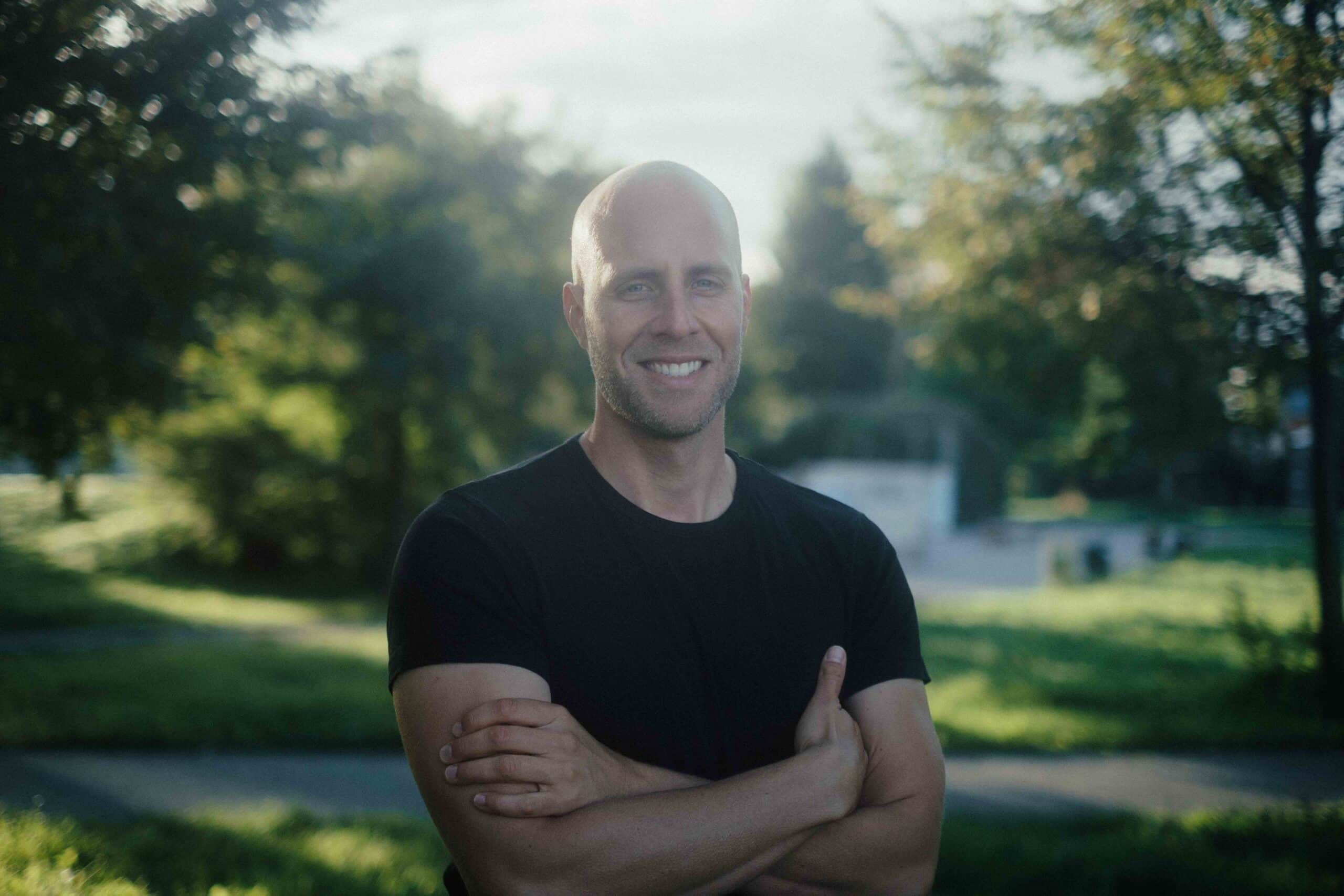 Timo Niessner, Referent, Mann mit schwarzem Shiirt am See Hände verschränkt